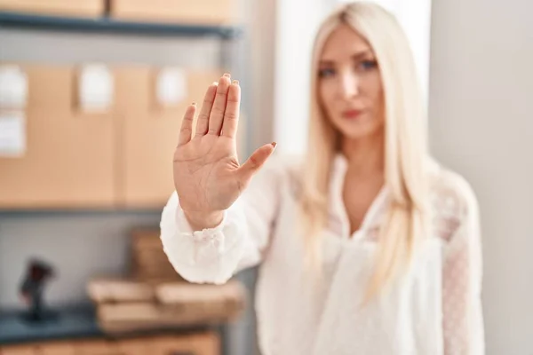Young blonde woman ecommerce business worker doing stop gesture with hand at office