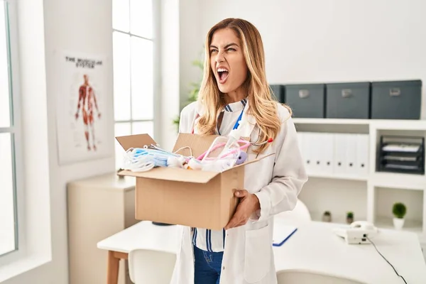 Young Blonde Doctor Woman Holding Box Medical Safety Items Angry — Stock Photo, Image