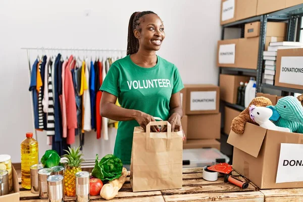 年轻的非洲裔美国志愿妇女在慈善中心准备装有食物的纸袋 — 图库照片