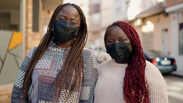 Two african american friends wearing medical mask standing together at street