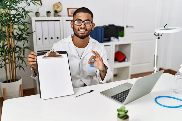 Young Indian Doctor Showing Blank Clipboard Doing Sign Fingers Smiling — Stock fotografie