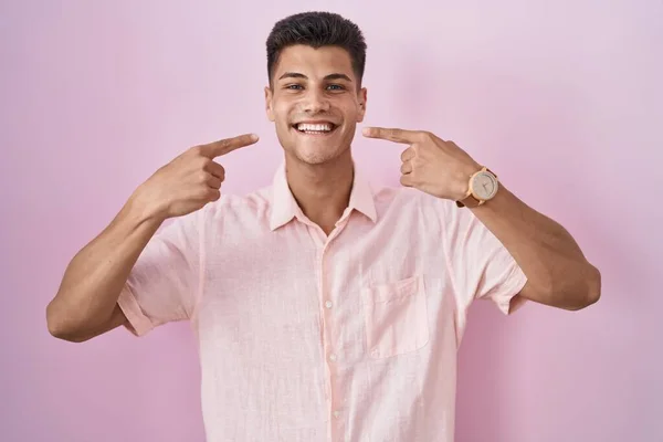 Молодой Латиноамериканец Стоит Розовом Фоне Весело Улыбаясь Показывая Пальцами Зубы — стоковое фото