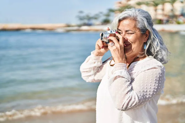 中年妇女在海滨用专业相机自信地微笑 — 图库照片