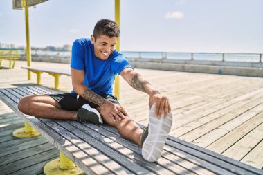 Genç İspanyol adam dışarıda bacak kaslarını esnetiyor.