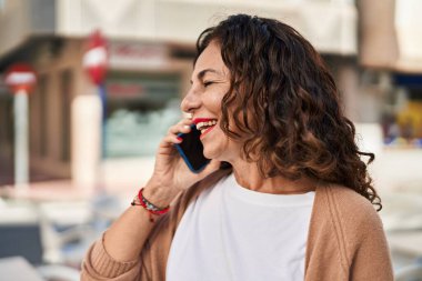 Middle age hispanic woman speaking on the phone outdoors