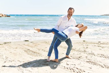 Orta yaşlı İspanyol çift gülümsüyor sahilde mutlu bir şekilde dans ediyor..