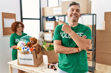 Bağışta gönüllü tişört giyen orta yaşlı bir adam yüzünde kocaman bir gülümsemeyle kameraya el ve parmak ile bakıyor.. 