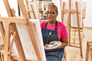 Kıdemli Afro-Amerikan kadın sanat stüdyosunda kendine güvenen çizimler yapıyor.