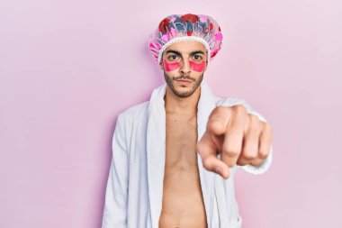 Bornoz ve duş başlığı takan genç İspanyol adam kamerayı işaret eden göz torbaları kullanıyor ve sen kendine güvenen ciddi görünüyorsun. 