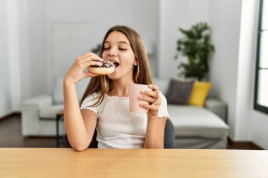 Çok tatlı bir kız kahvaltısını evde, masada yapıyor.