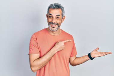 Gri saçlı yakışıklı orta yaşlı bir adam. Sıradan bir tişört giyiyor. Hayret ediyor ve kameraya gülümsüyor.. 