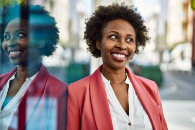 Güzel bir iş adamı Afro saçlı Amerikalı kadın şehirde mutlu ve kendinden emin bir şekilde gülümsüyor.