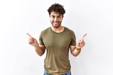 Hispanic man standing over isolated white background smiling confident pointing with fingers to different directions. copy space for advertisement 
