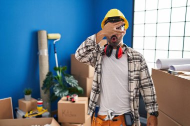 Sakallı, evde çalışan genç bir İspanyol adam. Şoka girmiş, yüzünü ve gözlerini kapamış, utangaç ifadesiyle parmaklarından bakıyor.. 