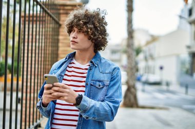 Genç İspanyol adam şehirde akıllı telefon kullanıyor.