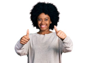 Genç Afro-Amerikalı kadın, günlük giysiler giyip, olumlu jestler yapıyor, gülümsüyor ve başarı için seviniyor. kazanan jest. 
