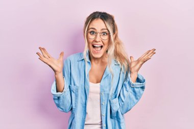 Güzel, genç, sarışın bir kadın gündelik kıyafetler ve gözlük takıp çılgınlığı kutluyor ve başarıya hayret ediyor. Kolları açık, gözleri açık, heyecanlı bir şekilde çığlık atıyor. Kazanan konsept 