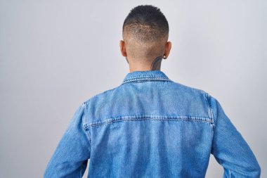 Genç İspanyol adam izole edilmiş arka planda dikiliyor geriye bakıyor ve kollarını vücuduna dikiyor. 