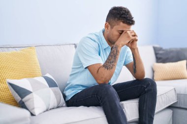 Afrikalı Amerikalı adam evdeki kanepede otururken stresli.