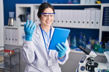 Young woman scientist using touchpad at laboratory