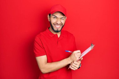 Sakallı, kurye üniformalı, pano tutan seksi bir ifadeyle kameraya bakan, neşeli ve mutlu yüzlü bir İspanyol.. 