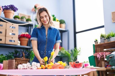 Young woman florist make bouquet of flowers at florist
