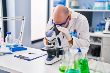 Genç bilim adamı laboratuvarda mikroskop kullanıyor.