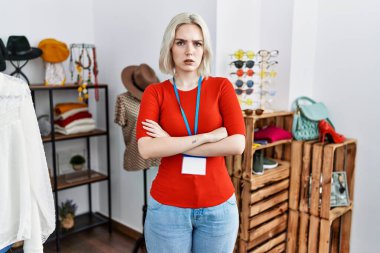 Perakende mağazasında müdür olarak çalışan genç beyaz kadın şüpheci ve gergin, yüzünde çapraz kollu tasvip etmeyen ifade. negatif kişi. 