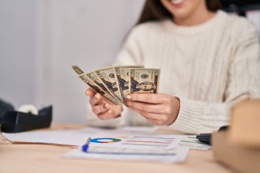 Genç kadın ecommerce iş işçisi ofiste dolar sayıyor