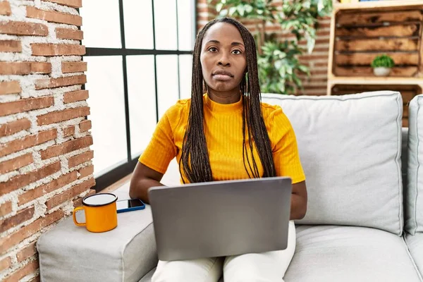 Африканская Женщина Сидит Диване Используя Ноутбук Дома Серьезным Выражением Лица — стоковое фото