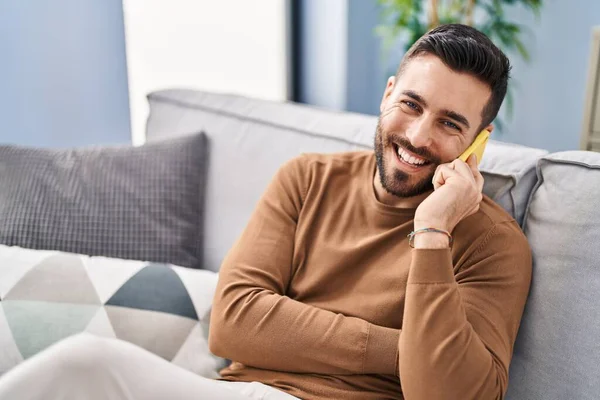 Young Hispanic Man Talking Smartphone Sitting Sofa Home — Stok fotoğraf