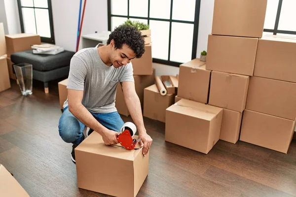 Genç İspanyol adam gülümsüyor yeni evinde mutlu bir paket kutusu var..