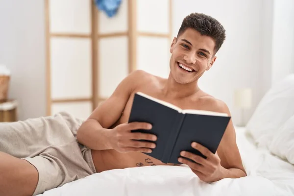 Young Hispanic Man Reading Book Lying Bed Bedroom — 图库照片