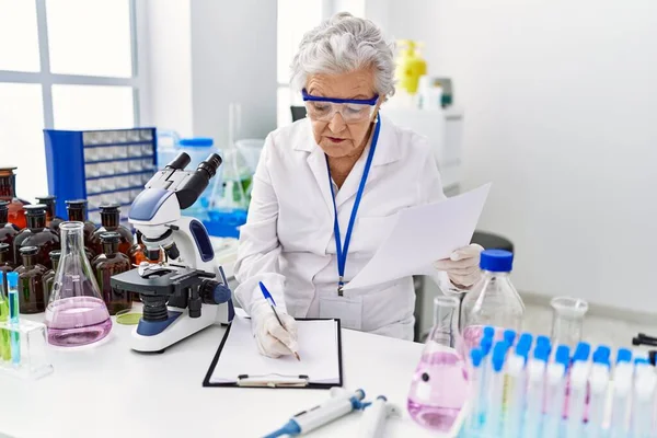 Senior Mulher Cabelos Grisalhos Vestindo Uniforme Cientista Escrevendo Área Transferência — Fotografia de Stock