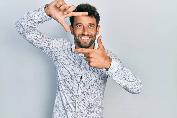 髭を生やしたハンサムな男は カジュアルでエレガントなシャツを着て 幸せな顔をした手と指でフレームを作って笑っている 創造性と写真の概念 — ストック写真