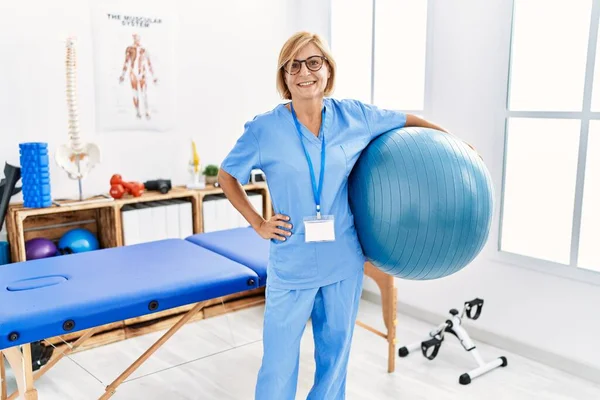 Blonde Frau Mittleren Alters Physiotherapeutenuniform Hält Fitnessball Klinik — Stockfoto