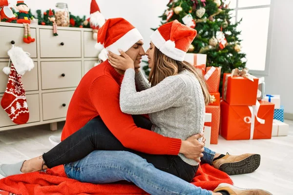 크리스마스 모자쓰고 키스하는 바닥에 앉아서 집에서 껴안고 — 스톡 사진
