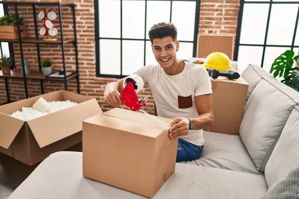 Jonge Spaanse Man Glimlachend Zelfverzekerd Verpakking Kartonnen Doos Nieuw Huis — Stockfoto
