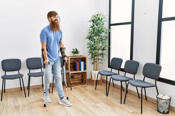 Young Redhead Man Walking Using Crutches Clinic Waiting Room — Stockfoto
