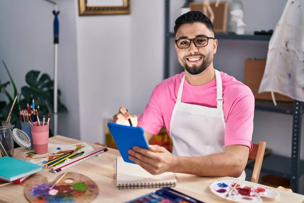 Young arab man artist drawing on notebook using touchpad at art studio