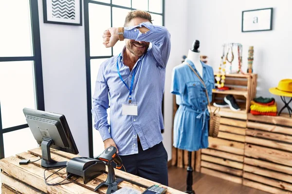 Middle age man working as manager at retail boutique smiling cheerful playing peek a boo with hands showing face. surprised and exited 
