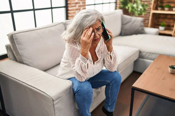 Middle age woman worried talking on the smartphone at home