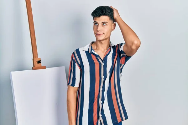 Young Hispanic Man Standing Close Empty Canvas Confuse Wonder Question —  Fotos de Stock