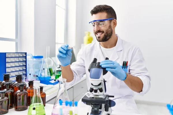 Young Hispanic Man Wearing Scientist Uniform Using Microscope Laboratory — Stock Photo, Image