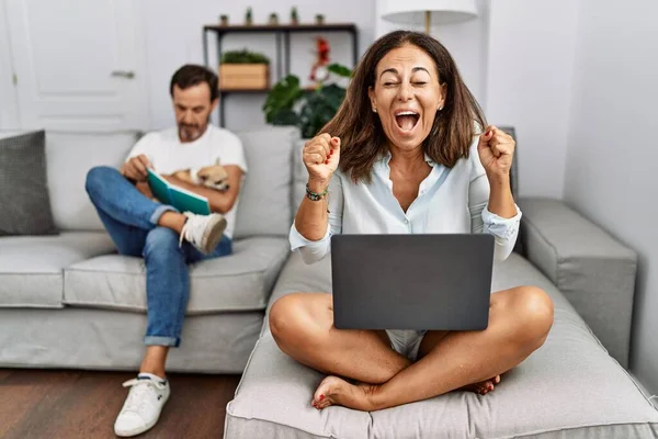 Hispanic Middle Age Couple Home Woman Using Laptop Celebrating Mad — Φωτογραφία Αρχείου