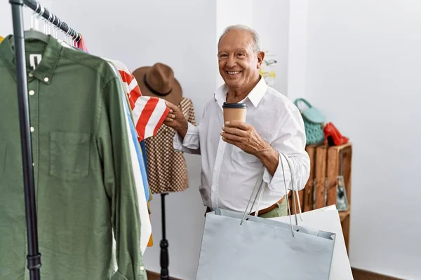Senior man customer choose clothes drinking coffee at clothing store