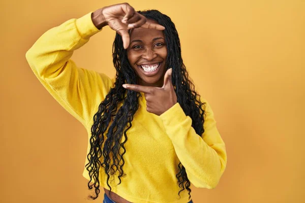 Африканська Жінка Стоїть Над Жовтим Фоном Посміхається Роблячи Рамку Руками — стокове фото