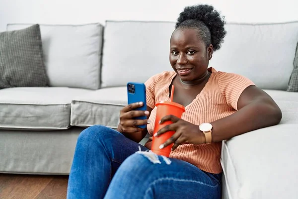 Young African American Woman Using Smartphone Drinking Soda Home — Φωτογραφία Αρχείου