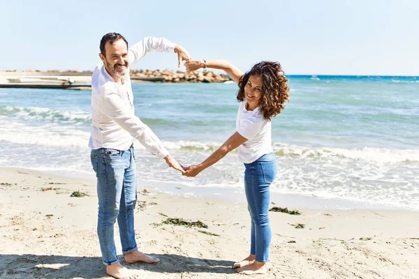 Orta Yaşlı Gülümseyen Bir Spanyol Çift Kumsalda Kollarıyla Kalp Hareketi — Stok fotoğraf