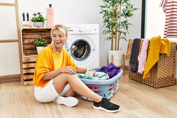 Young Caucasian Woman Putting Dirty Laundry Washing Machine Winking Looking — Stockfoto